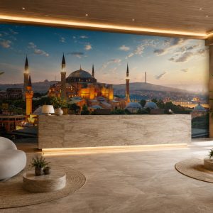 Gün batımı gökyüzü altında ihtişamla yükselen Ayasofya-i Kebir Cami-i Şerifi illüstrasyonu; mermer traverten resepsiyon bankosu, yuvarlak sehpa ve LED tavan aydınlatmasıyla mekan girişlerinde etkileyici bir atmosfer oluşturur.