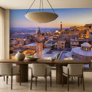 Batan güneşin kızıllığı altında uzanan tarihi Mardin panoraması temalı duvar kağıdı; oval ahşap yemek masası, krem sandalyeler ve geniş çanak sarkıt aydınlatmayla yemek odalarına estetik bir zerafet katar.