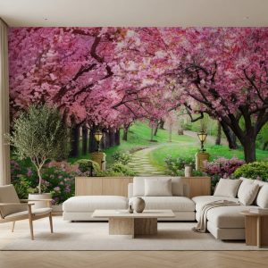 Pembe çiçek açmış kiraz (sakura) ağaçlarıyla kaplı tünel şeklinde patika yol ve yeşil bahçe manzarası; krem köşe koltuk, ahşap sehpa ve saksıda zeytin ağacıyla salona derinlik ve canlılık katar.