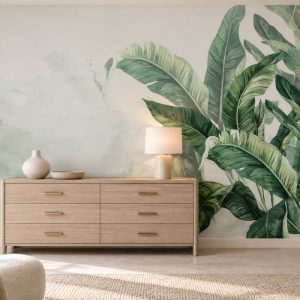 Soft krem ve sisli yeşil-beyaz fon üzerine resmedilmiş zümrüt yeşili ve fıstık yeşili tonlarında tropikal dev yapraklar detaylı duvar kağıdı; geniş ahşap konsol şifonyer, dairesel seramik abajur ve natürel aksesuarlarla yatak odası ve antre alanlarında şık, elit ve huzurlu bir ortam vadeder.