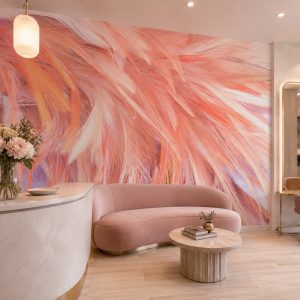 Canlı somon, mercan ve mor dokunuşlu tüy efektli duvar kağıdı; pudra pembe kavisli kanepe, ahşap yuvarlak yan sehpa ve modern bekleme bankıyla ticari veya kişisel alanlara lüks ve romantik bir dokunuş kazandırır.