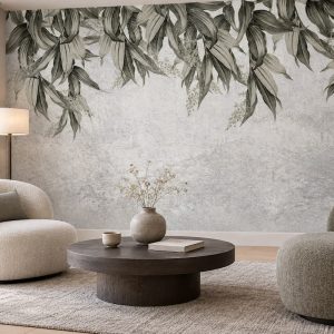 Beton/mermer dokulu açık gri zemin üstünden sarkan adaçayı yeşili ve zeytin tonlarında okaliptüs/söğüt yaprakları detaylı duvar kağıdı; krem dairesel berjer koltuklar, koyu ahşap dairesel orta sehpa ve natürel halıyla salonda minimalist, huzurlu ve modern bir oturma alanı yaratır.