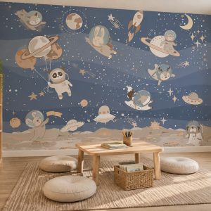 Mavi yıldızlı uzay fonunda sevimli astronot hayvanlar (panda, tavşan, kedi, ayı), roketler, gezegenler ve Ufo illüstrasyonlu çocuk odası duvar kağıdı; ahşap mini sehpa, yuvarlak yer minderleri ve örme halıyla tasarlanmış dinlenme alanı.