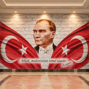 Beyaz tuğla zemin üzerinde Atatürk portresi, ay-yıldızlı bayrak kanatları ve 